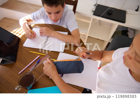 Parent and child engaged in homeschooling at a table Parent and child engaged in homeschooling at a table 119898383