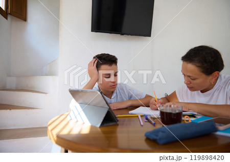 Mother helping son with homework at dining table Mother helping son with homework at dining table 119898420