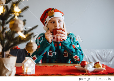 Young girl enjoying a warm drink in Christmas attire, embracing holiday spirit, festive cheer, seasonal traditions, cozy Christmas moment. 119899910