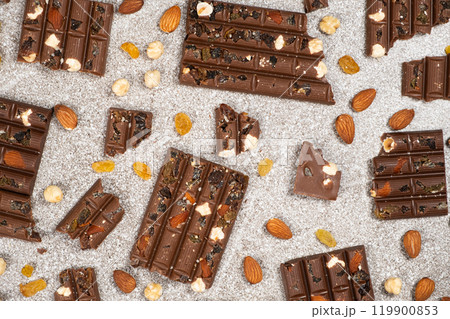 Broken chocolate pieces with nuts and raisins on a stone background top view 119900853