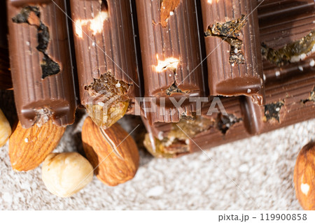 Broken chocolate pieces with nuts and raisins on a stone background top view Broken chocolate pieces with nuts and raisins on a stone background top view 119900858