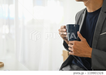 Cropped shot of businessman with a mug of coffee relaxing in the office 119901328