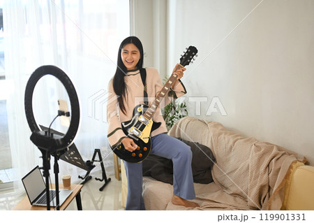 Young cheerful woman playing electric guitar during a live session Young cheerful woman playing electric guitar during a live session 119901331