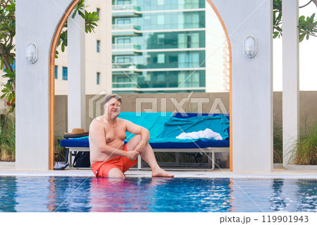 A large Caucasian man put his feet in the pool at a luxury hotel A large Caucasian man put his feet in the pool at a luxury hotel 119901943