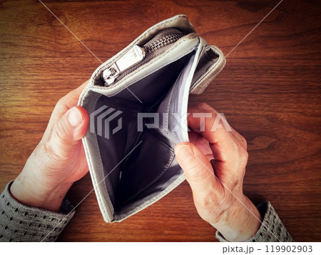 机の上で空っぽの財布を開ける高齢女性の手元 119902903