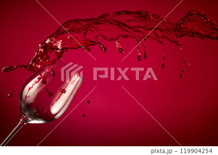 Glass and red wine splash on a red background. Glass and red wine splash on a red background. 119904254