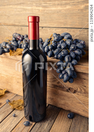 Bottle of red wine with blue grapes on a wooden table. Bottle of red wine with blue grapes on a wooden table. 119904264
