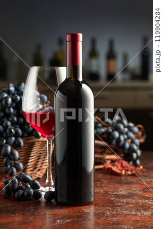 Bottle and glass of red wine with grapes on a vintage table. Bottle and glass of red wine with grapes on a vintage table. 119904284
