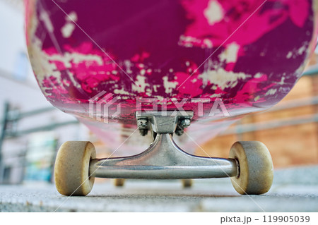 Used pink skateboard against stone wall in urban setting 119905039