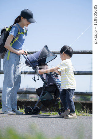 川沿いの河川敷でベビーカーを押す母親と下の子の面倒やお世話をするかわいい兄 縦 川沿いの河川敷でベビーカーを押す母親と下の子の面倒やお世話をするかわいい兄 縦 119905085
