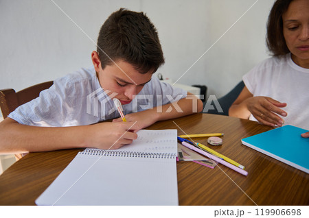 Young boy focused on doing homework with parental support Young boy focused on doing homework with parental support 119906698