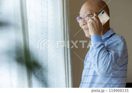 外を眺めながら電話をするシニア男性 119908135
