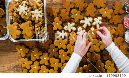 Flat lay. Crafting gingerbread cookie sandwiches with eggnog buttercream, presented on a rustic wooden table for Christmas gifting. 119908199