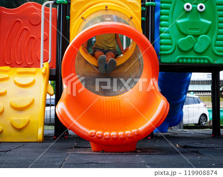 Children playing in the playground during summer vacation. Cute girl having fun on a colorful slide in an outdoor park. Children playing in the playground during summer vacation. Cute girl having fun on a colorful slide in an outdoor park. 119908874