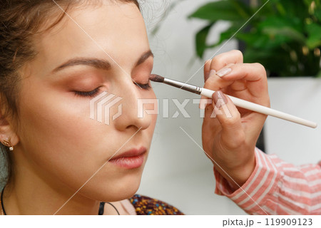 The process of creating makeup. Makeup artist working with a brush on the face of the model. The process of creating makeup. Makeup artist working with a brush on the face of the model. 119909123
