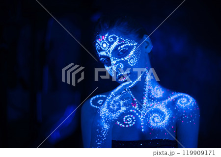 Body art on the body and hand of a girl glowing in the ultraviolet light. 119909171