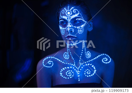 Body art on the body and hand of a girl glowing in the ultraviolet light. 119909173