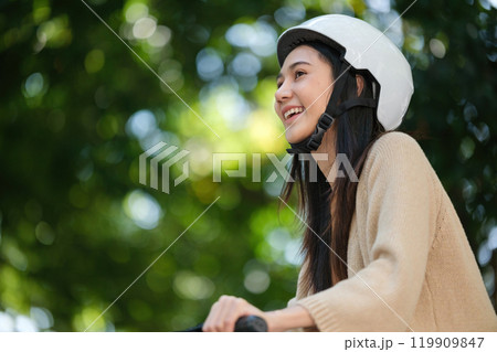 A woman is smiling while wearing a helmet and sitting on a bicycle 119909847