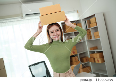 A woman wearing a green shirt is holding two boxes on her head 119909859