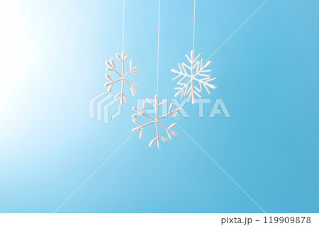 Snowflake made from cotton swabs hanging on string against blue background. Minimalist winter decoration. Christmas and winter holidays concept 119909878