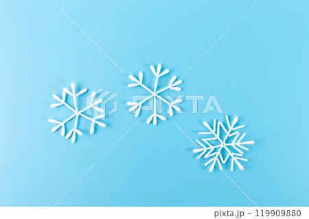 Snowflake made from cotton swabs hanging on string against blue background. Minimalist winter decoration. Christmas and winter holidays concept 119909880