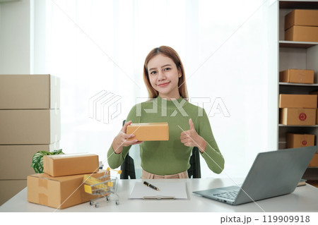 A woman is sitting at a desk with a laptop and a stack of cardboard boxes A woman is sitting at a desk with a laptop and a stack of cardboard boxes 119909918