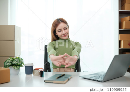 A woman is sitting at a desk with a laptop and a notebook A woman is sitting at a desk with a laptop and a notebook 119909925