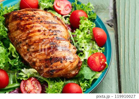 Grilled chicken breast ( fillet ) with lattuce salad and cherry tomatoes . Top view 119910027
