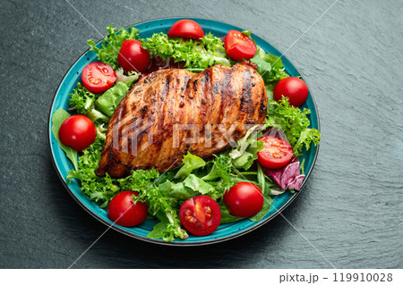Grilled chicken breast ( fillet ) with lattuce salad and cherry tomatoes . Top view 119910028