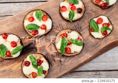 Italian mini pizza . Aubergine (eggplant ) with mozzarella cheese and basil . On rustic background Italian mini pizza . Aubergine (eggplant ) with mozzarella cheese and basil . On rustic background 119910175