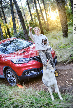 Woman taking pictures close to a car parked in a forest path. Woman taking pictures close to a car parked in a forest path. 119911931