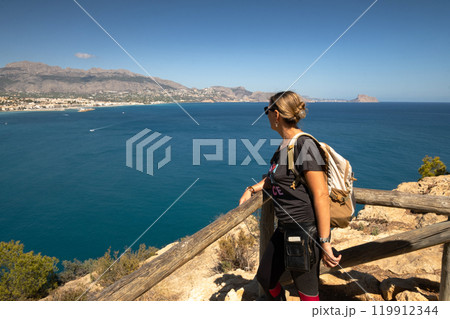 Girl with backpack looking at the sea 119912344