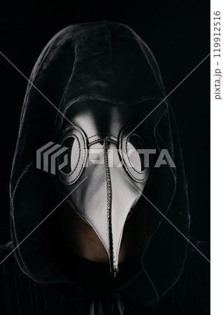 Plague doctor with crow-like mask on black background. Creepy mask for Halloween, historical costume 119912516