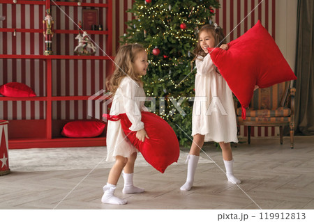 Little girls in the pillow fight game have fun in the holiday room 119912813