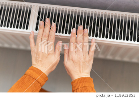 female hands are warming themselves near the radiator female hands are warming themselves near the radiator 119912853