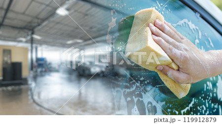 A hand with a washcloth washes a car window. A hand with a washcloth washes a car window. 119912879
