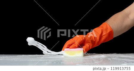 Hand in orange rubber glove hold cleaning brush sponge and wipe soap foam bubble splash in air over black background, Cleaning floor splash bubble soap foam splatter over bathroom Hand in orange rubber glove hold cleaning brush sponge and wipe soap foam bubble splash in air over black background, Cleaning floor splash bubble soap foam splatter over bathroom 119913755