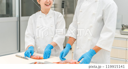 魚を調理するコックコート姿の男女スタッフ(セントラルキッチン・調理師・料理人・生鮮市場・食品加工) 魚を調理するコックコート姿の男女スタッフ(セントラルキッチン・調理師・料理人・生鮮市場・食品加工) 119915141
