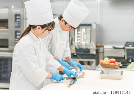 魚を調理するコックコート姿の男女スタッフ(調理師・料理人・生鮮市場・食品加工) 魚を調理するコックコート姿の男女スタッフ(調理師・料理人・生鮮市場・食品加工) 119915143