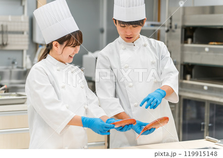 魚を調理するコックコート姿の男女スタッフ(調理師・専門学校・料理人・生鮮市場・食品加工) 魚を調理するコックコート姿の男女スタッフ(調理師・専門学校・料理人・生鮮市場・食品加工) 119915148