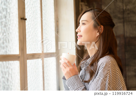 窓際でコーヒーを飲む女性 119916724