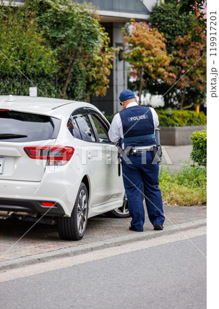 交通違反をした運転手に反則切符を発行する警察官 交通違反をした運転手に反則切符を発行する警察官 119917201