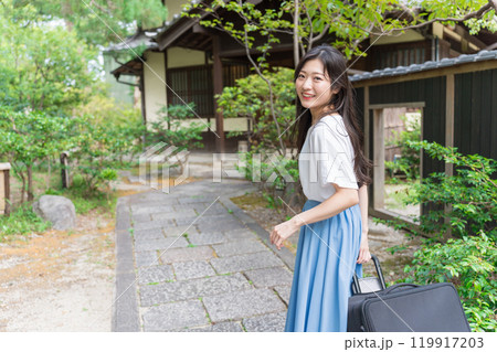 キャリーケースを引いて田舎に帰省する若い女性　旅行イメージ  119917203