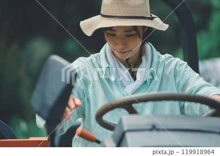 トラクターの運転に戸惑う若い女性 119918964
