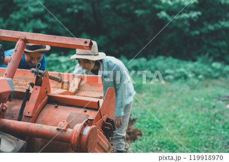 トラクターロータリーの土落としをする農家 119918970