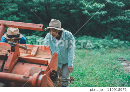 トラクターロータリーのメンテナンスをする農家 119918971