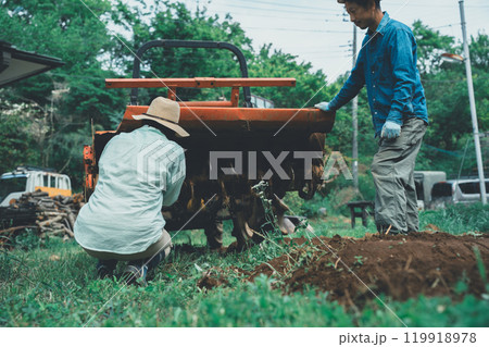 トラクターロータリーの泥落としをする農家 119918978