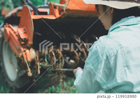 トラクターロータリーの泥落としをする若い女性 トラクターロータリーの泥落としをする若い女性 119918980
