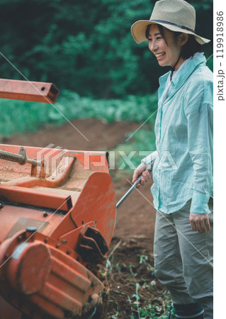 トラクターロータリーの土落としをする女性 119918986