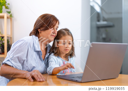 Granddaughter and grandmother using laptop Granddaughter and grandmother using laptop 119919035